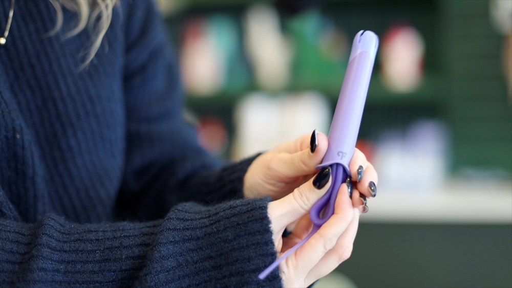 Woman shows how to insert the Fillow Disc into applicator shows a purple folded menstrual fillow disc