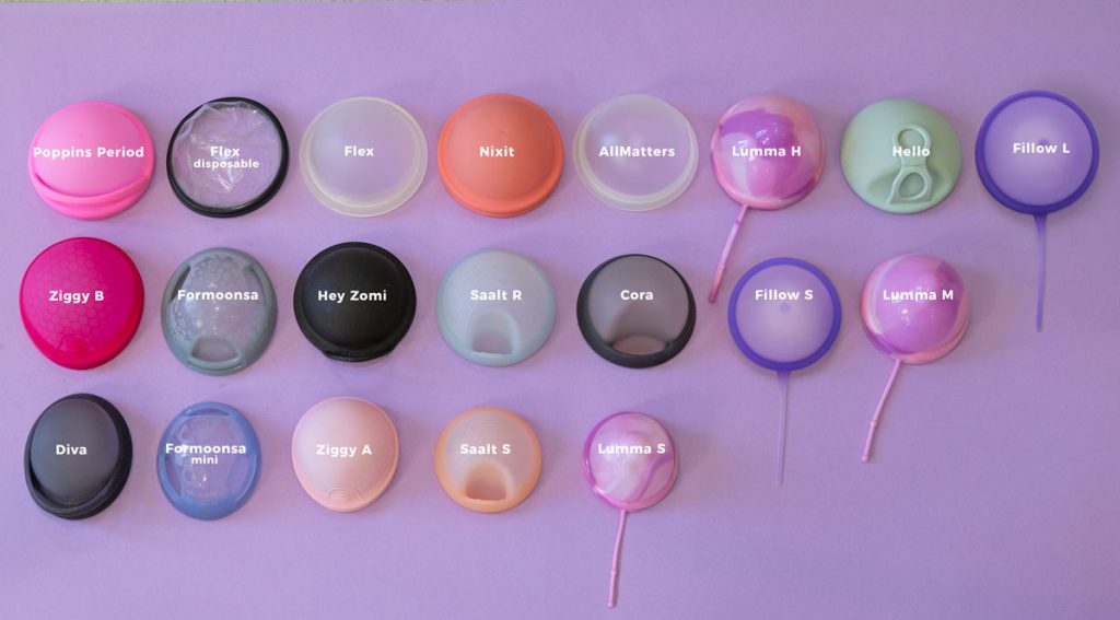 A selection of menstrual discs in colorful silicone laid out side by side on a purple background